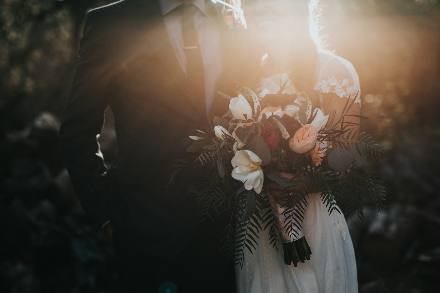 A newlywed couple holding a bouquet in warm afternoon light
